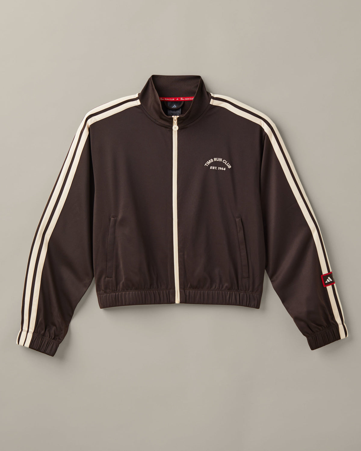 Women’s cropped espresso-brown adidas® track top with a cream zipper, cream 3-Stripes, and a Tims Run Club chest graphic. - Image #2