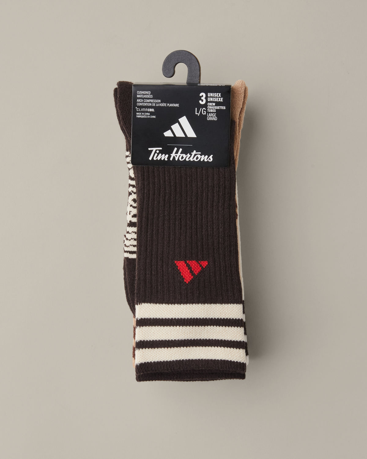 Three pairs of men’s adidas® crew socks in tan, cream, and espresso brown with striped cuffs and red adidas® logos. - Image #3