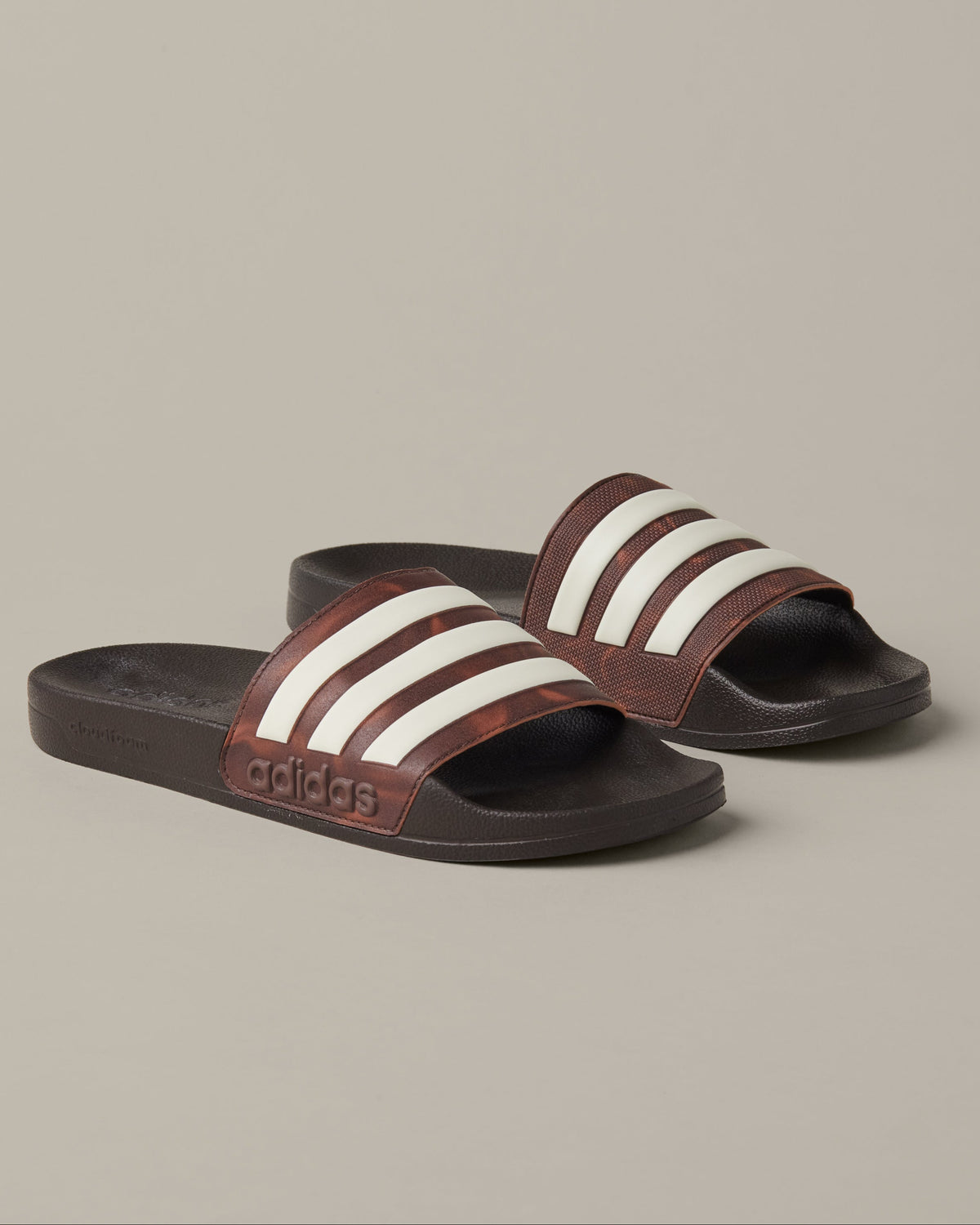 Espresso-brown adidas® Adilette Aqua slides with cream 3-Stripes across the foot straps.