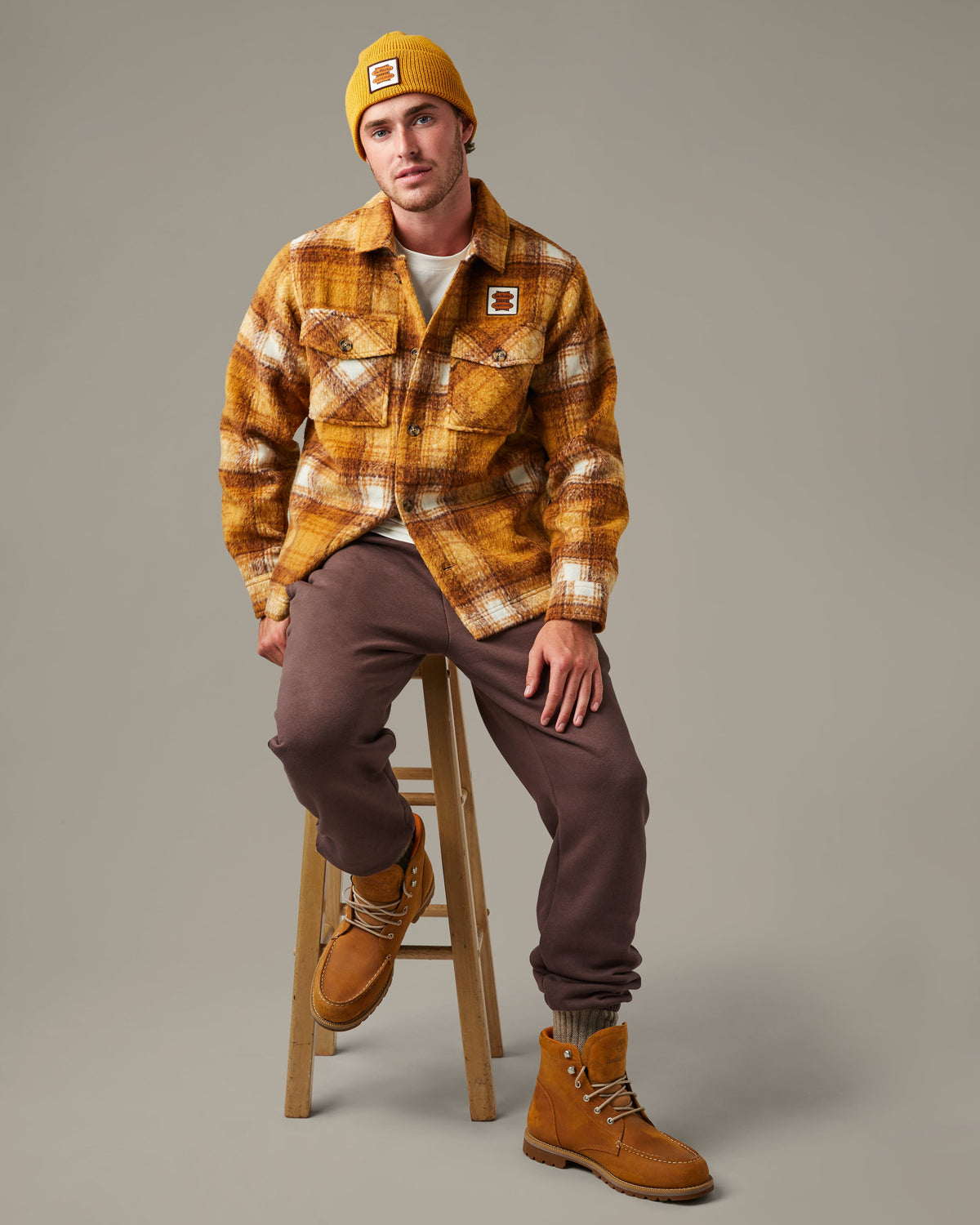Yellow, brown, and cream plaid Tim Hortons shacket with a button front, two flap chest pockets, and a small logo patch. | Surchemise Tim Hortons à carreaux jaunes, bruns et crème, avec fermeture à bouton sur le devant, deux poches poitrine à rabat et un petit écusson à logo.